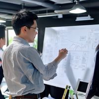 王超，磁力网站产品总监，在白板前向团队讲解产品路线图，展现清晰的产品思维